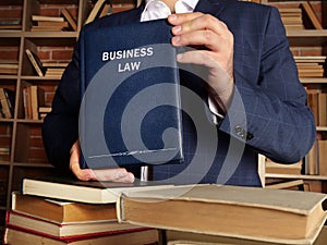 BUSINESS LAW book in the hands of a attorney. Commercial lawÂ regulatesÂ corporateÂ contracts, hiring practices, and the
